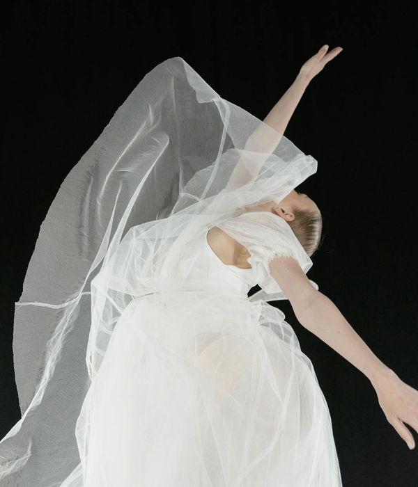 Woman performing a fluid cardio movement in a dark studio with amber light accents.